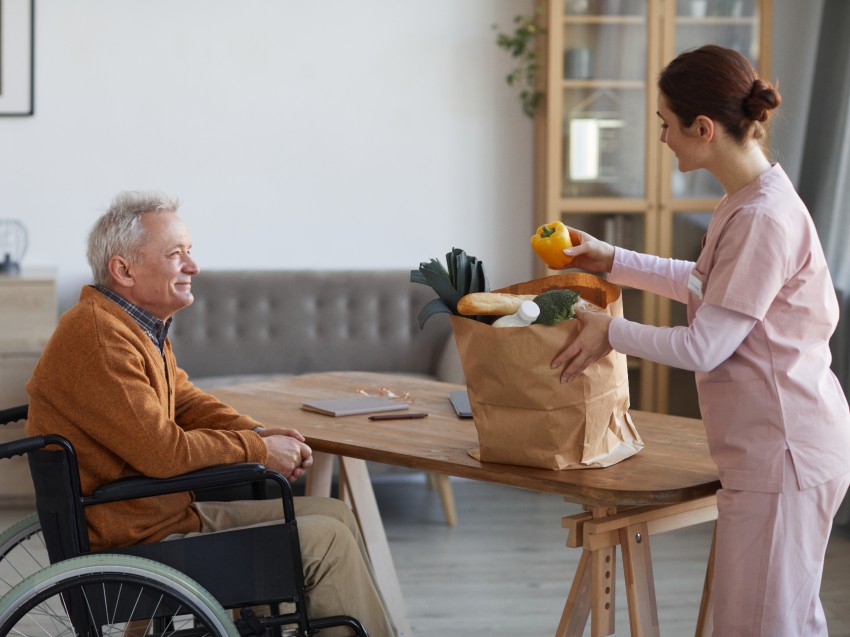 Opiekunka dająca zakupy seniorowi w domu spokojnej starości